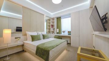 A modern hotel room with a neatly made bed, a desk, and a small table.