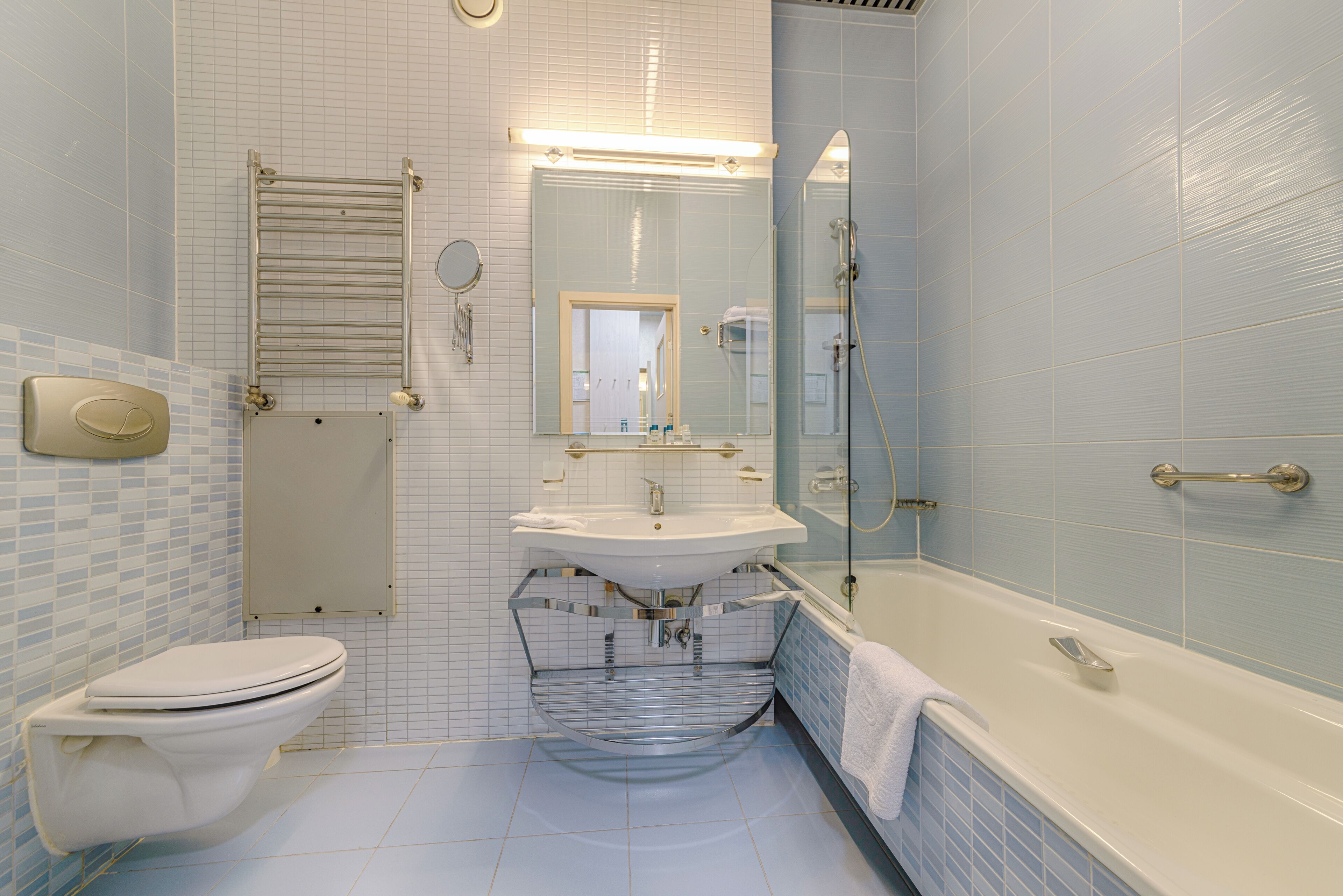 A bathroom with a toilet, sink, mirror, and bathtub.