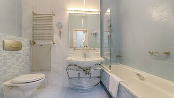 A bathroom with a toilet, sink, mirror, and bathtub.