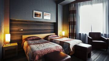 Habitación de hotel con dos camas, cabecero de madera, una silla y un ventanal con cortinas.