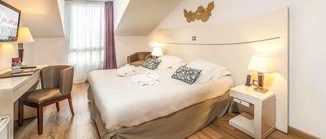 A hotel room with a bed, bedside tables, a desk, a chair, and a large window with curtains.
