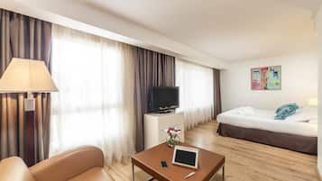 Una habitación de hotel con una cama, un televisor, un escritorio con lámpara y una mesita de centro.