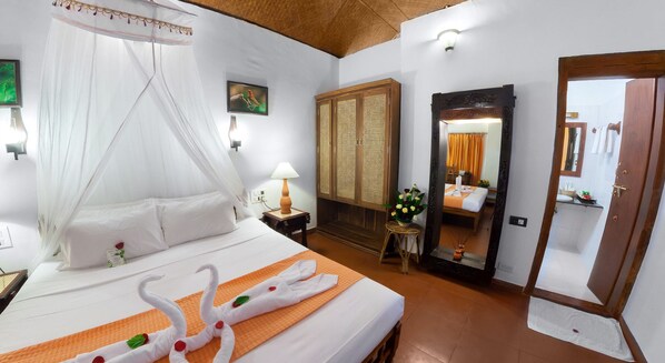 A hotel room with a bed, a canopy, a nightstand, a lamp, a mirror, and a wardrobe.