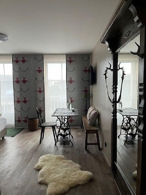 Ein Zimmer mit einem Esstisch, Stühlen, einer Couch, einem großen Spiegel und einem Fellteppich.