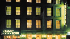 A multi-story hotel with illuminated signage, multiple windows, and a visible entrance with a reception area. - Classic Hotel Kaarst (Kaarst)