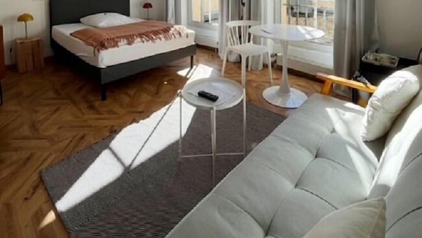 A modern bedroom with a bed, a sofa, a dining table, and a large window. - Classic Hotel Kaarst (Kaarst)