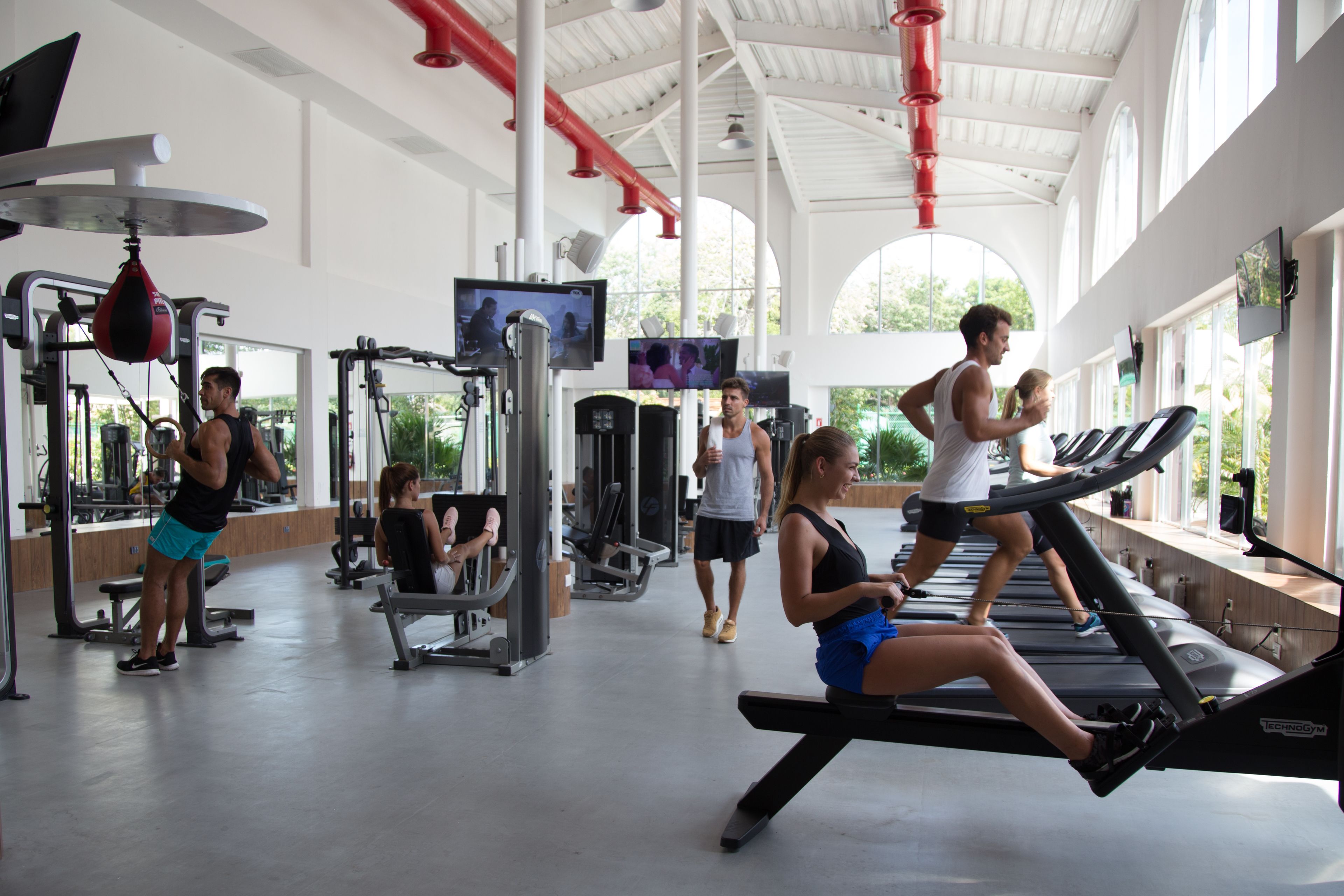 Un gimnasio con cintas de correr, máquinas de pesas y un saco de boxeo.