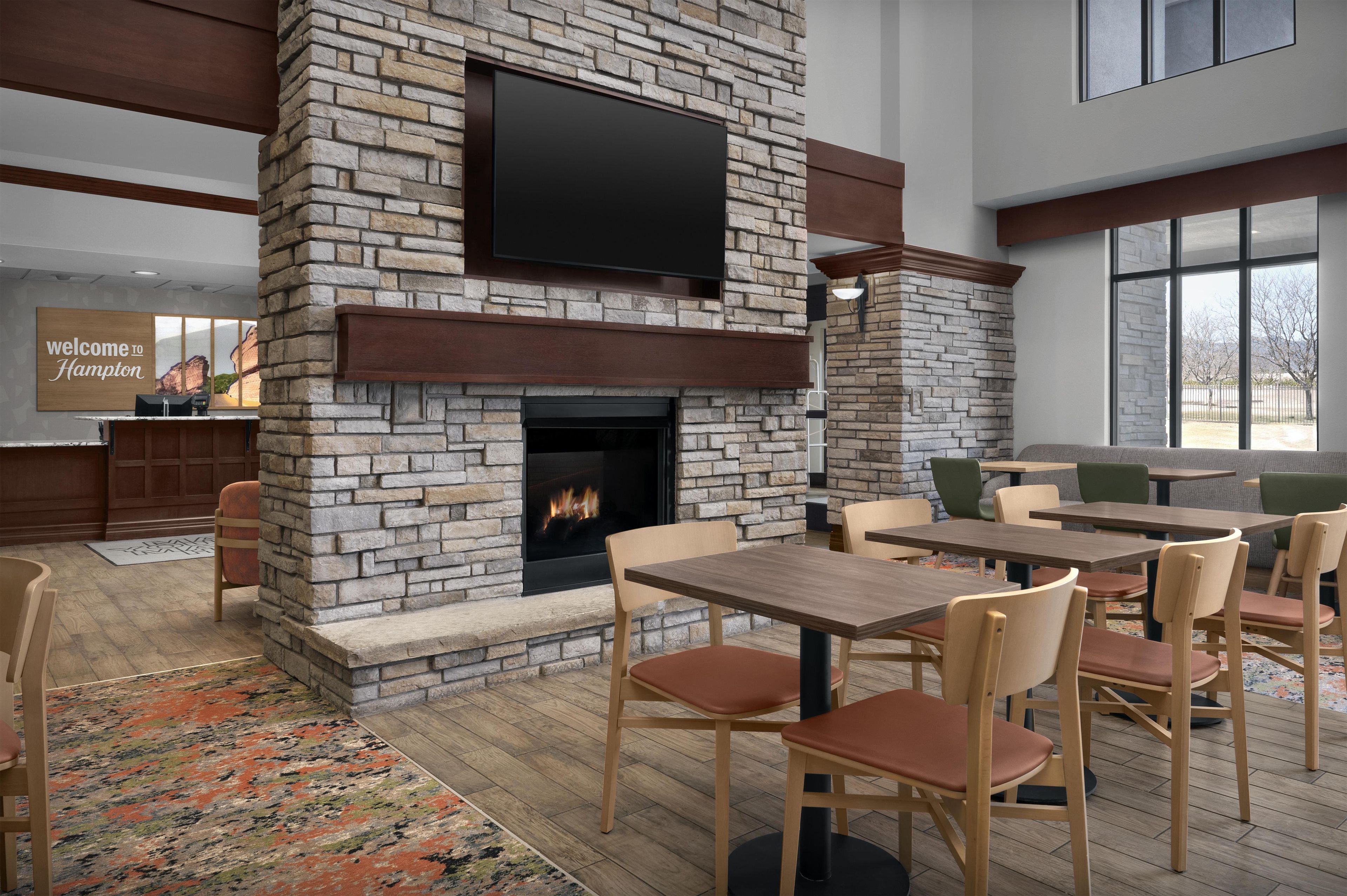 A modern interior with a stone fireplace, flat-screen TV, and outdoor seating area.