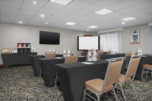 A conference room with tables, chairs, a projector screen, and a television. - Hampton Inn & Suites Colorado Springs/I-25 South (Colorado Springs)