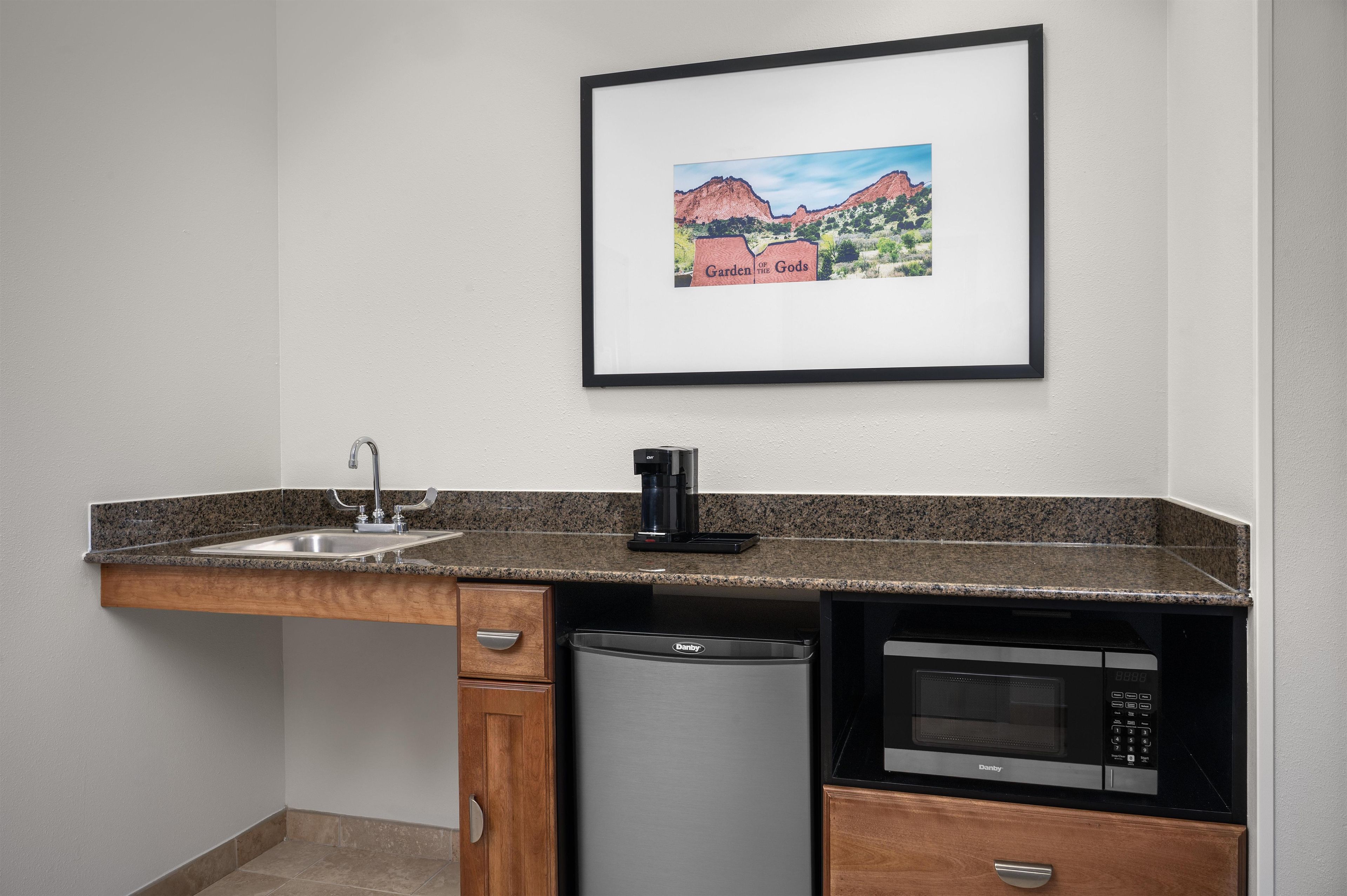 A kitchen with a sink, a coffee maker, a dishwasher, and a microwave.