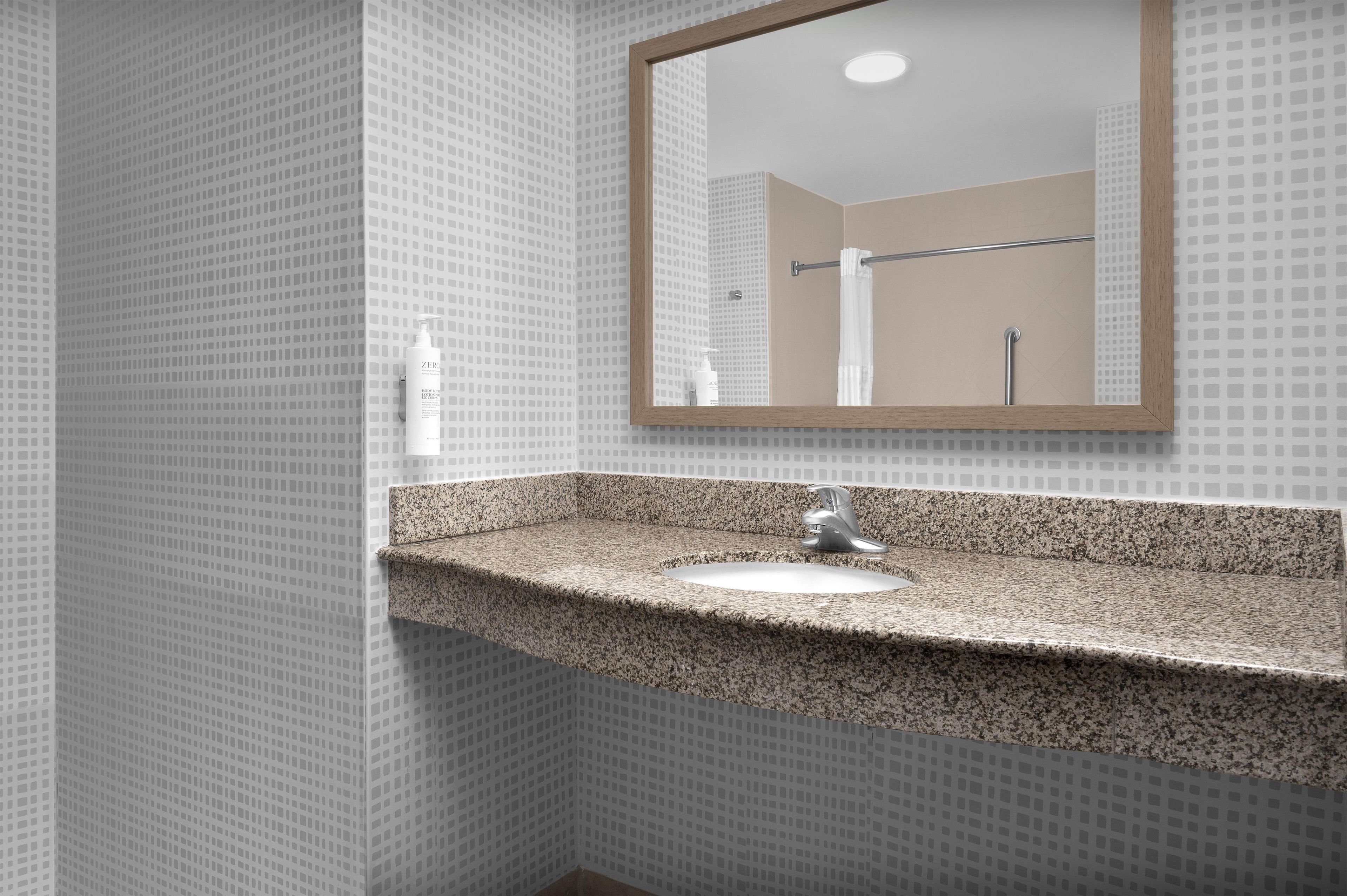 A bathroom with a granite countertop sink, a mirror, and a towel rack.