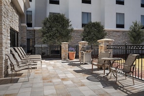 An outdoor patio with stone walls, a grill, and outdoor seating. - Hampton Inn & Suites Colorado Springs/I-25 South (Colorado Springs)