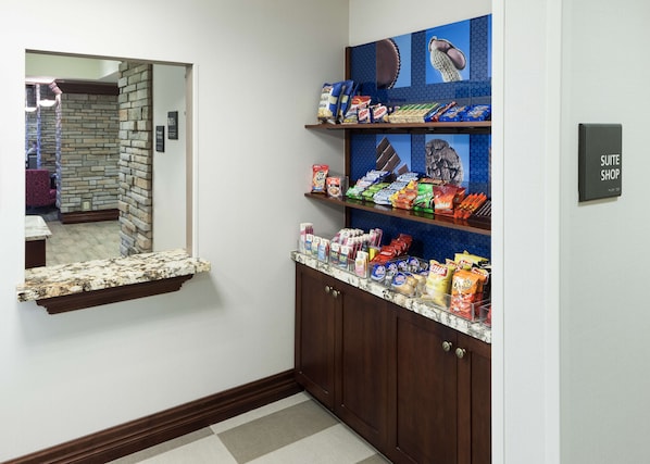Un couloir d’hôtel avec un bar proposant divers en-cas et un miroir qui reflète la pièce.