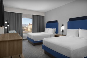 A hotel room with two beds, a desk, a chair, and a large window with a view.