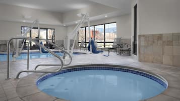 A pool area with a hot tub, a lounge chair, and a table with chairs.