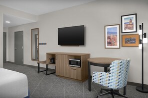 A hotel room with a bed, a desk with a microwave, a chair, a flat-screen TV, and a framed picture on the wall. - Hampton Inn & Suites Colorado Springs/I-25 South (Colorado Springs)