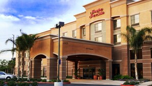 Entrada de hotel con señalización clara, zona de estacionamiento y jardines delanteros.