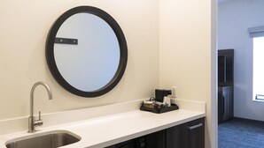 Un baño con lavabo, espejo y cafetera.