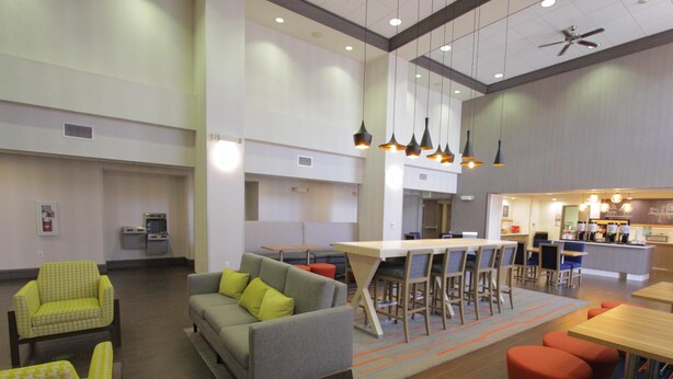 Un moderno vestíbulo de hotel con zona de bar, arreglos de asientos y kitchenette.