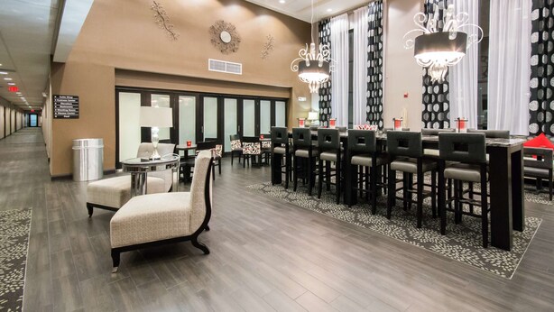 A hotel lobby with a reception desk, seating area, and a large mirror. - Hampton Inn & Suites Orlando-John Young Pkwy/S. Park (Orlando)
