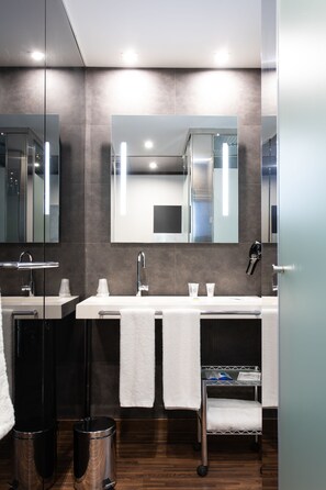 A modern bathroom with two sinks, a large mirror, and a towel rack. - Hotel Ciudad de Móstoles (Mostoles)
