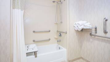Un baño con bañera, barras de apoyo, toallero y ducha.