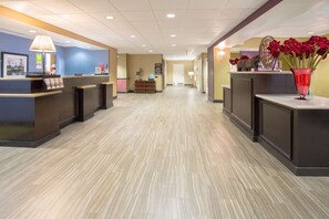 A hotel reception area with a reception desk, a waiting area, and a hallway leading to other rooms.