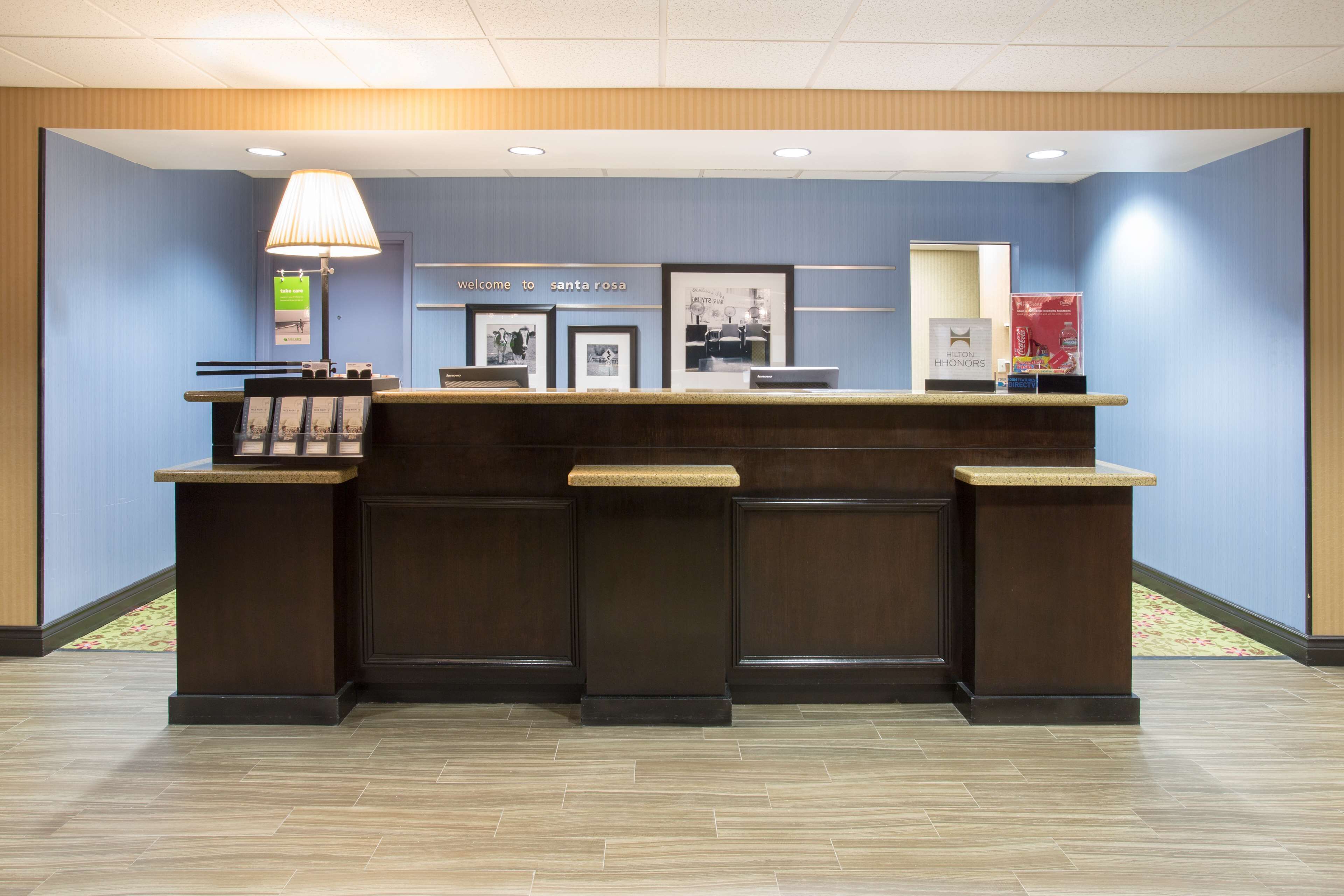 A reception desk with a dark wood finish, a sign reading "Welcome to Santa Rosa," and framed pictures on the wall.