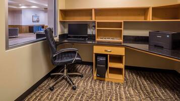 Un espacio de trabajo con escritorio, silla, computadora, impresora y estanterías.
