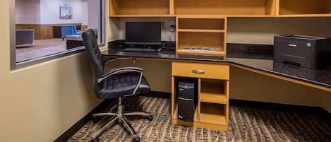 Un espacio de trabajo con escritorio, silla, computadora, impresora y estanterías.