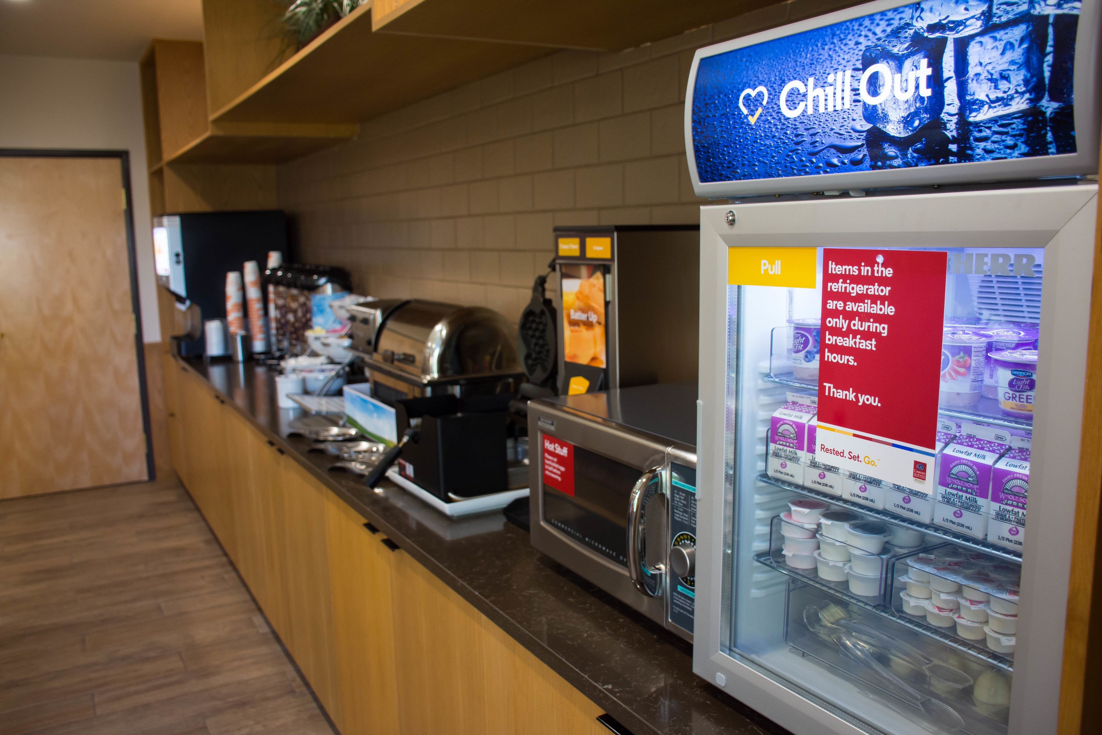 A breakfast area with a microwave, toaster, and refrigerator stocked with dairy products.
