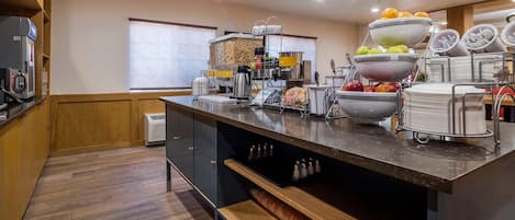 Una cocina moderna con una isla central, equipada con varios electrodomésticos, una cafetera y un frutero.