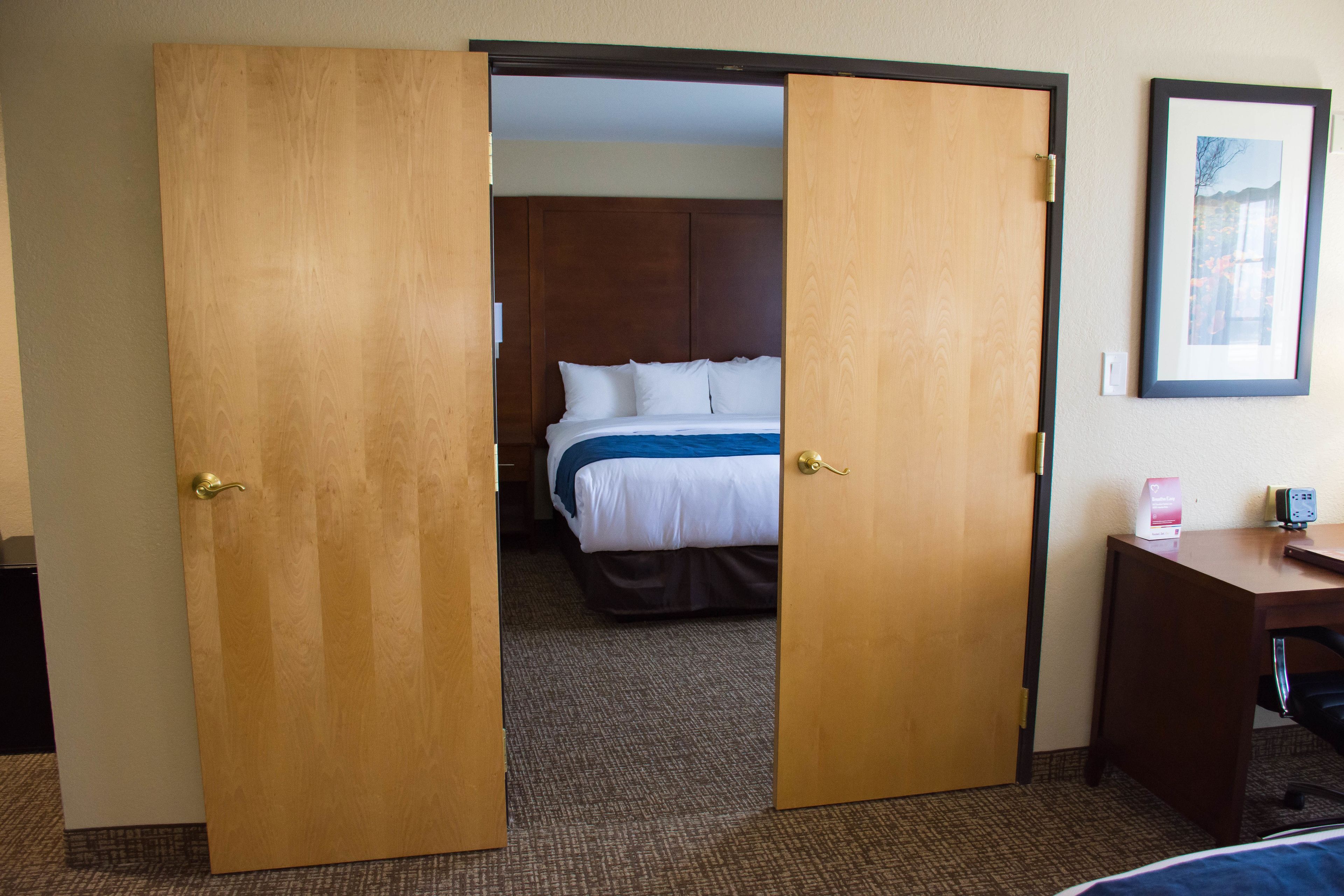 Une chambre d’hôtel avec un lit, un bureau et une porte donnant sur une autre pièce.