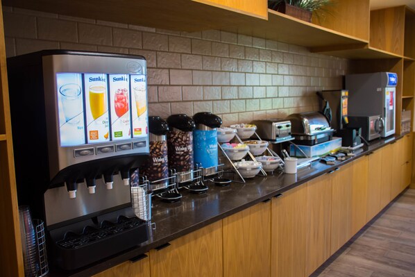 Una estación de autoservicio para bebidas con diversas opciones y una máquina de café.