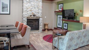 A living room with a fireplace, a television, and a sofa. - Hampton Inn Murphy (Murphy)