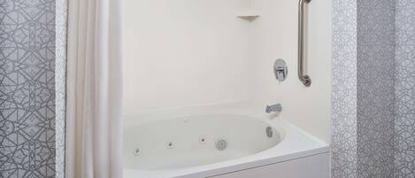 A modern bathroom with a freestanding bathtub, grab bars, and a showerhead.