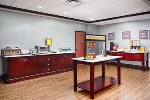 A breakfast area with a wooden counter, a coffee machine, and a fruit display. - Hampton Inn Melbourne-Viera (Melbourne)