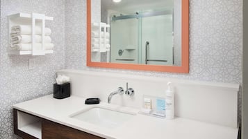 Un baño moderno con un espejo grande, un lavabo blanco y un box de ducha de vidrio.