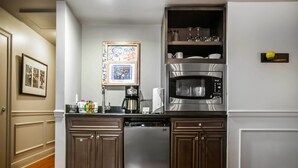 Una cocina moderna con armarios de madera oscura, un refrigerador de acero inoxidable, un microondas integrado y una cafetera.