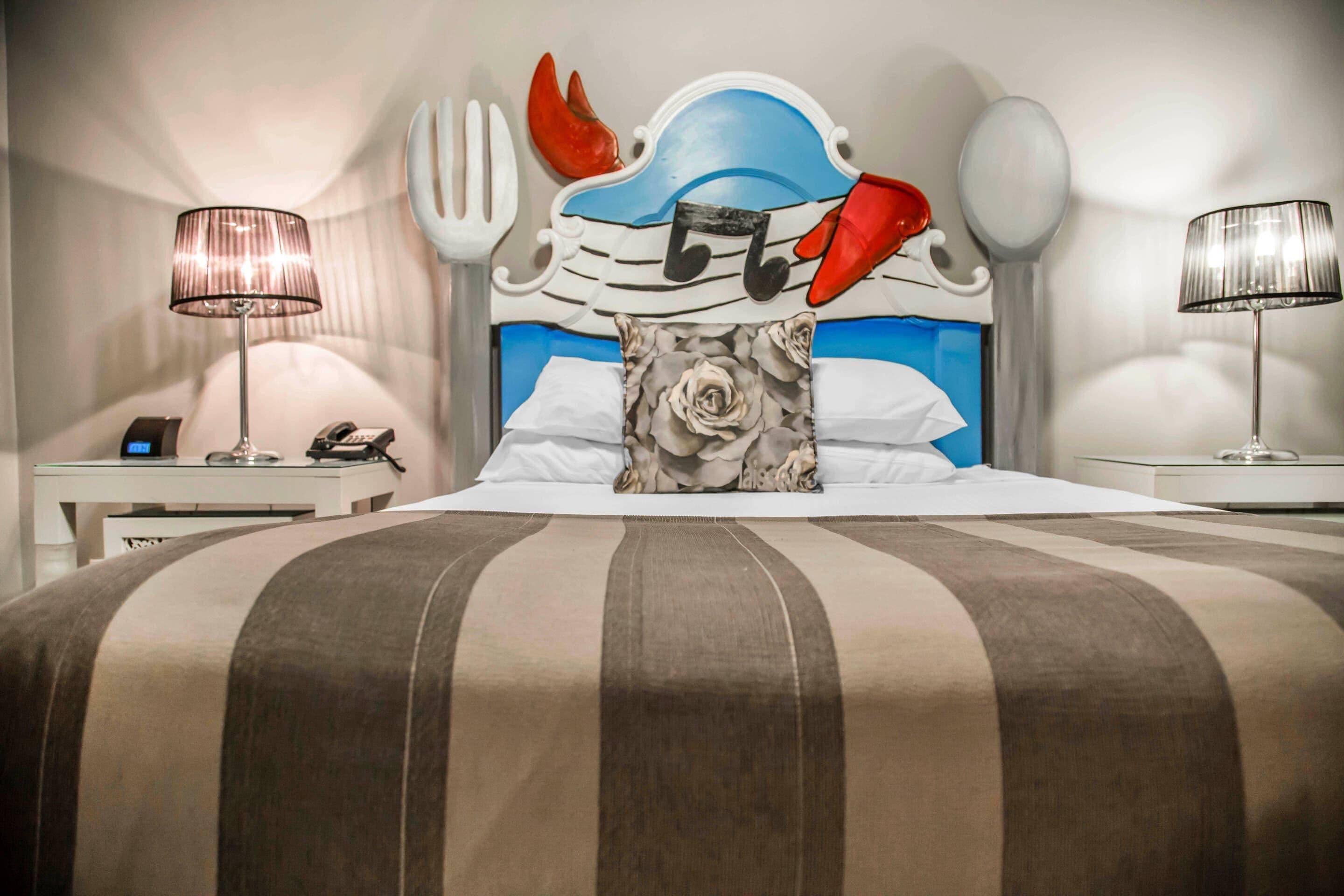 Une chambre d’hôtel avec un lit, deux tables de chevet, une lampe et un téléphone.