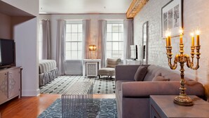 A modern living room with a sofa, a TV, a decorative candelabra, and a patterned rug.