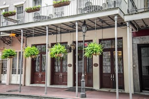 A building with a covered entrance, hanging planters, and a street lamp.