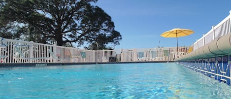 Una piscina al aire libre, sombrillas, sillones reclinables de piscina