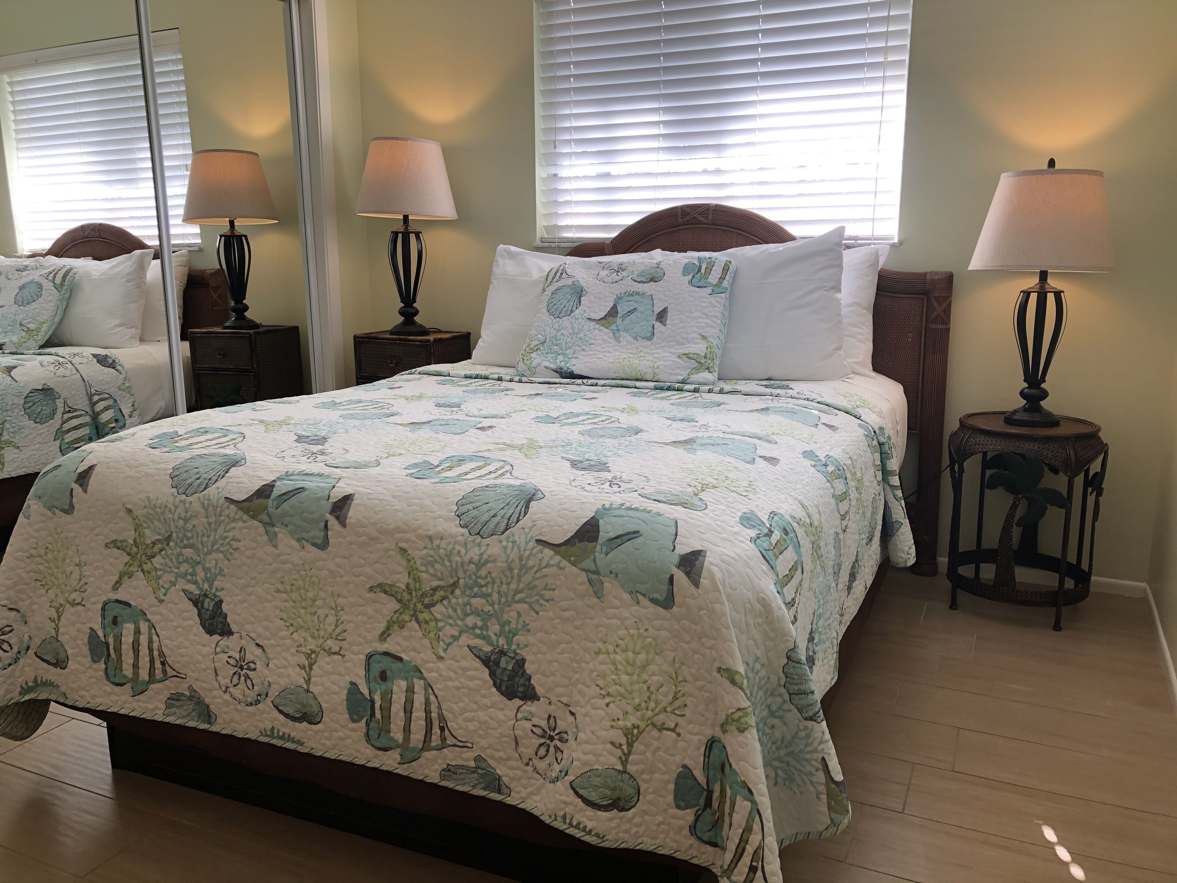 Un dormitorio con cama, dos mesitas de noche, lámparas y un espejo.