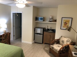 Una habitación compacta con cama, kitchenette, zona de comedor y una puerta que da a otra habitación.