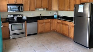 A kitchen with wooden cabinets, stainless steel appliances, and a tiled floor. - Addys Villas (Nokomis)