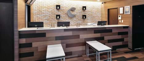 A reception desk with two computer stations, a brick-patterned wall, and a herringbone-patterned floor.