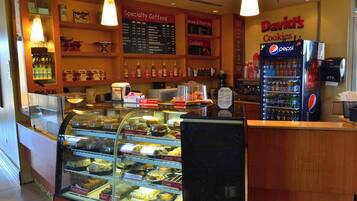 A bakery counter with a glass display case filled with pastries and a menu board above it listing specialty coffees and pastries.