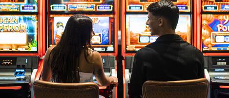 A casino with multiple slot machines labeled "CASH STACKS" and a person playing one of them.