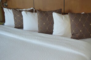 Un lit bien fait, avec du linge de lit blanc et des coussins à motifs.